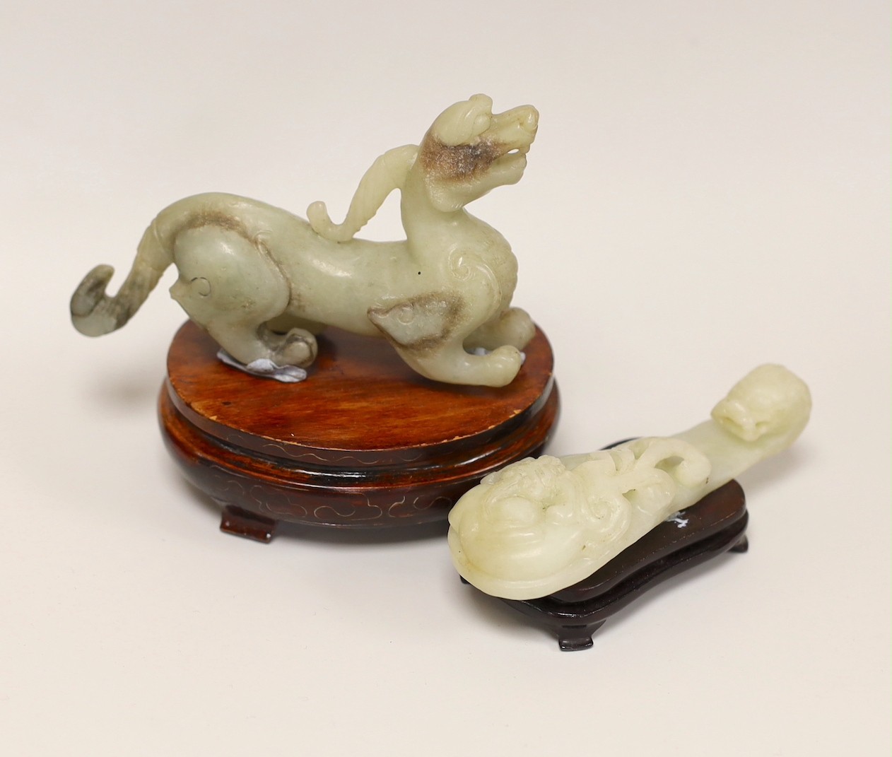 A Chinese pale celadon and grey jade mythical beast on stand and a pale celadon jade belt hook, mythical beast 11cms wide